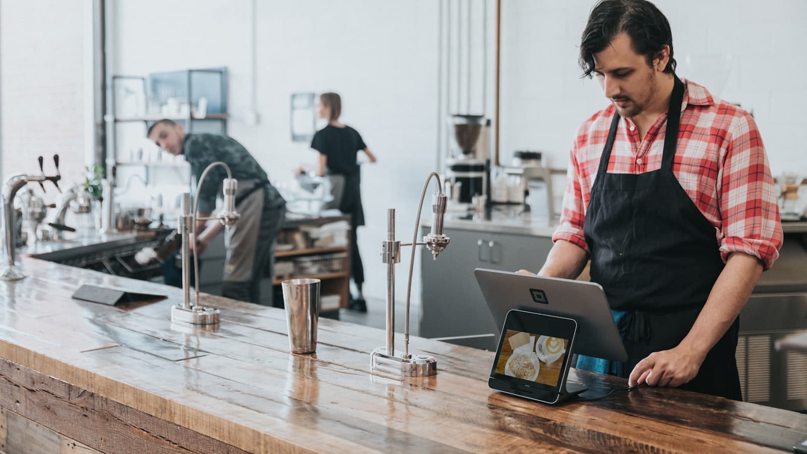 Barista mencatat pesanan lewat tablet kasir di meja bar kedai kopi