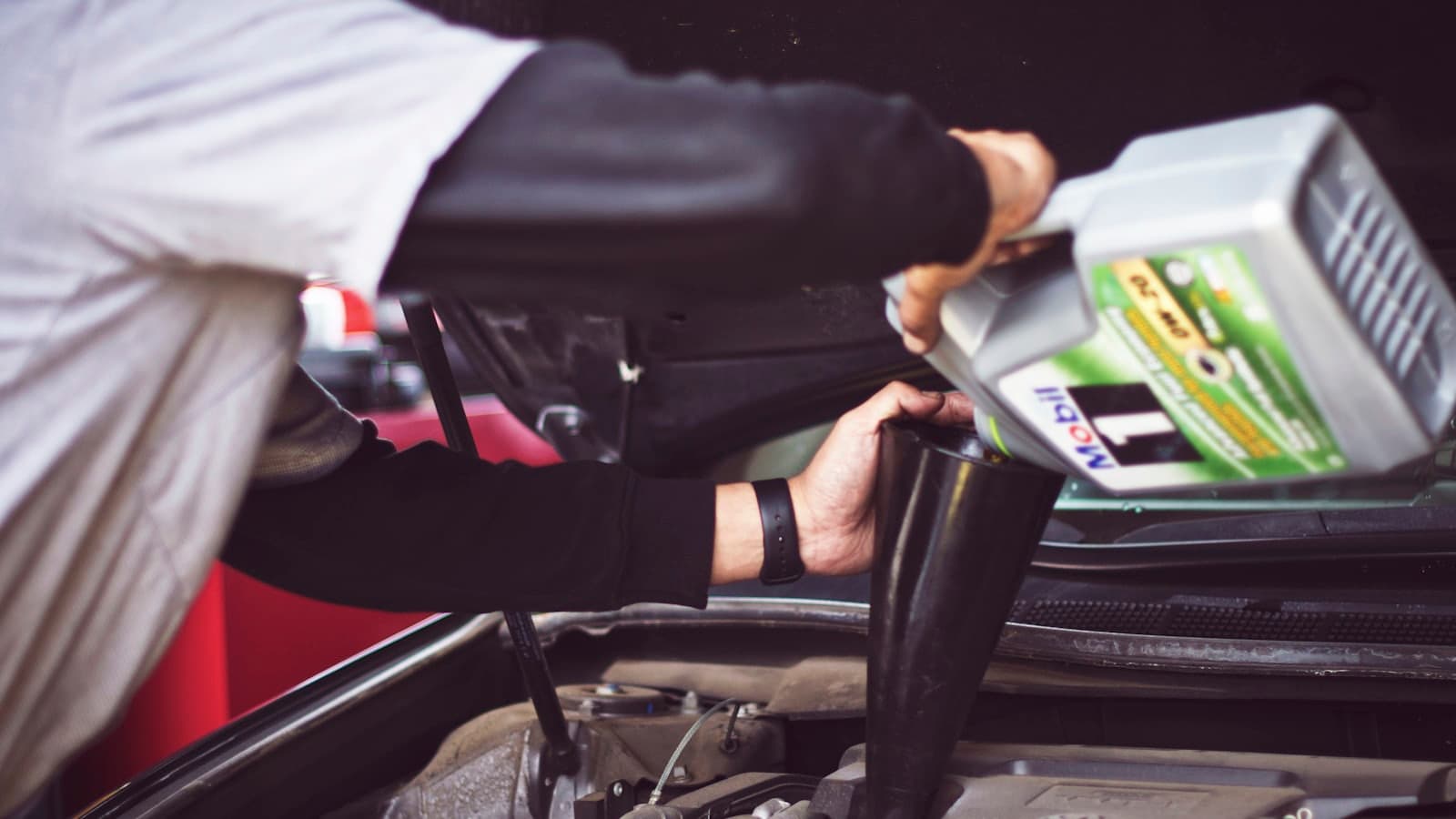 Teknisi bengkel memeriksa mesin mobil menggunakan alat diagnostik